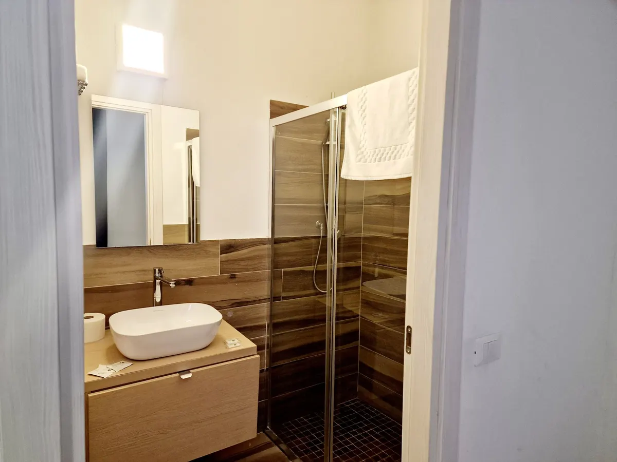 Bagno privato della camera quintupla con doccia in vetro e lavabo in appoggio