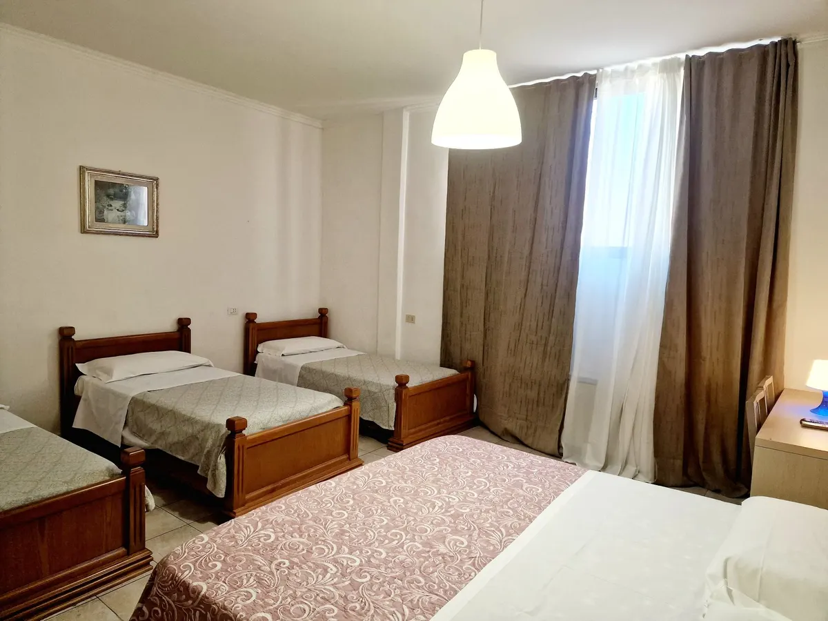 Camera quintupla con tre letti singoli e letto matrimoniale vicino alla finestra