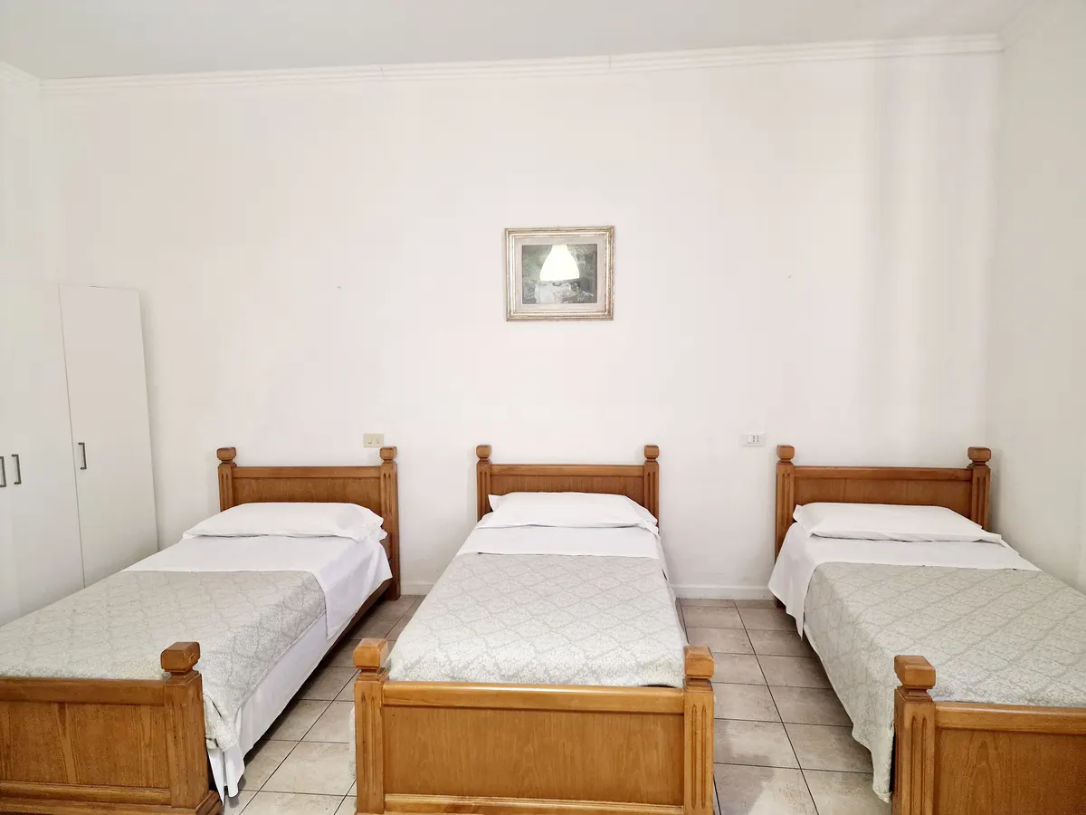 Camera tripla con tre letti singoli in legno all'Hotel Firenze 2000